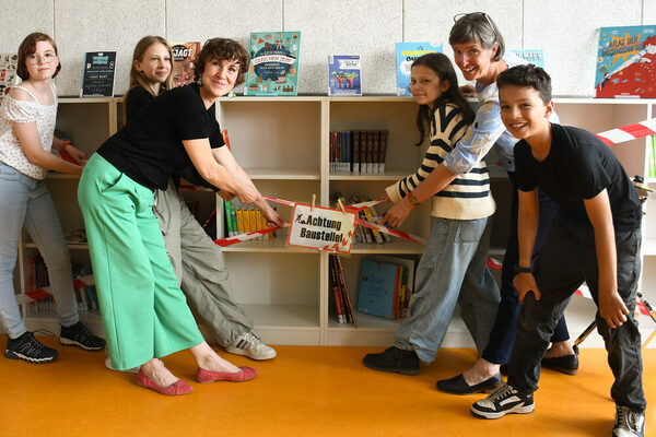 Kinder und Erwachsene vor einem Bücherregal